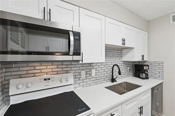 a kitchen with white cabinets a sink and white appliances