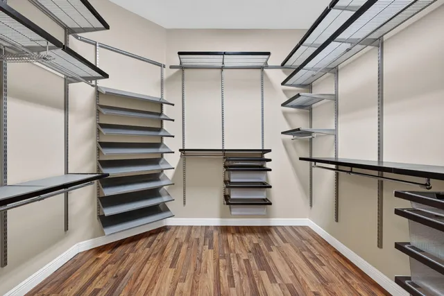 a view of walk in closet with wooden floor and shoes