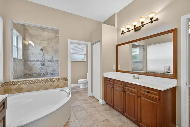 a spacious bathroom with a tub sink shower and mirror