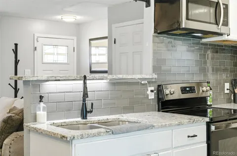 a kitchen with granite countertop a sink a stove and cabinets