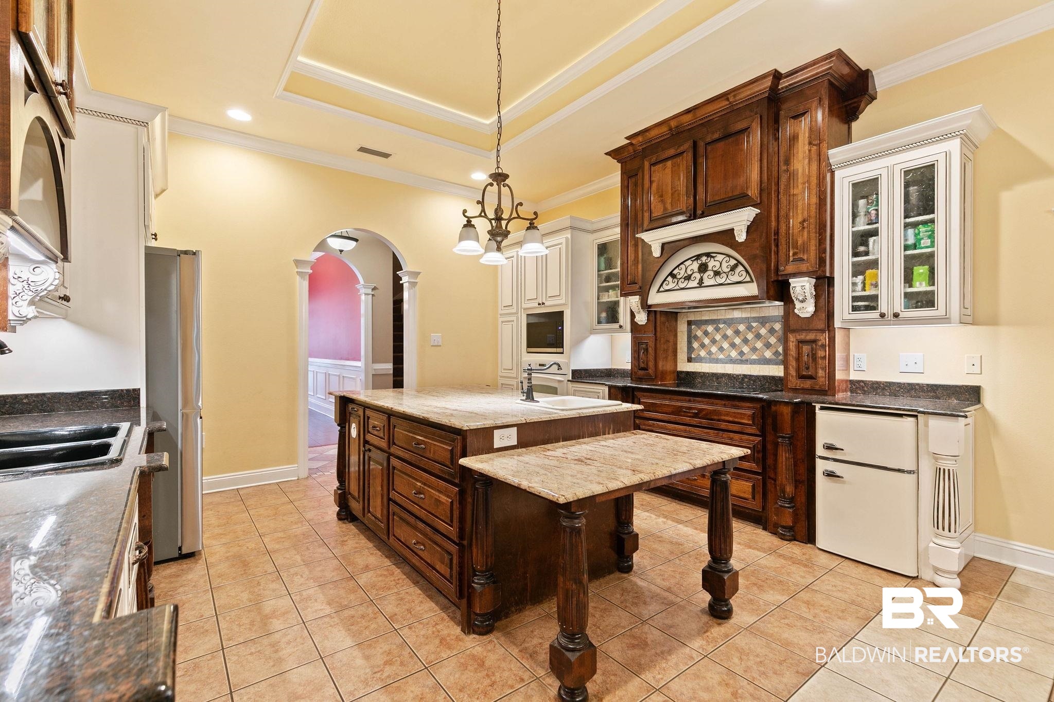 3668 Claridge Road North Mobile, AL 36608 - Photo 41 of 100 Kitchen featuring arched walkways, dark stone counters, dual tone cabinetry, glass insert cabinets, and freestanding refrigerator