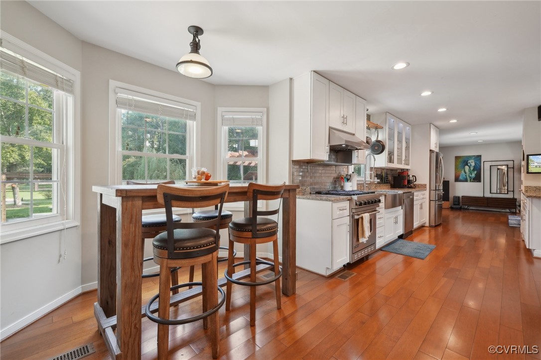 7101 Conifer Road Richmond, VA 23237 - Photo 20 of 50 a kitchen with stainless steel appliances kitchen island granite countertop a stove a refrigerator a sink a dining table and chairs with wooden floor