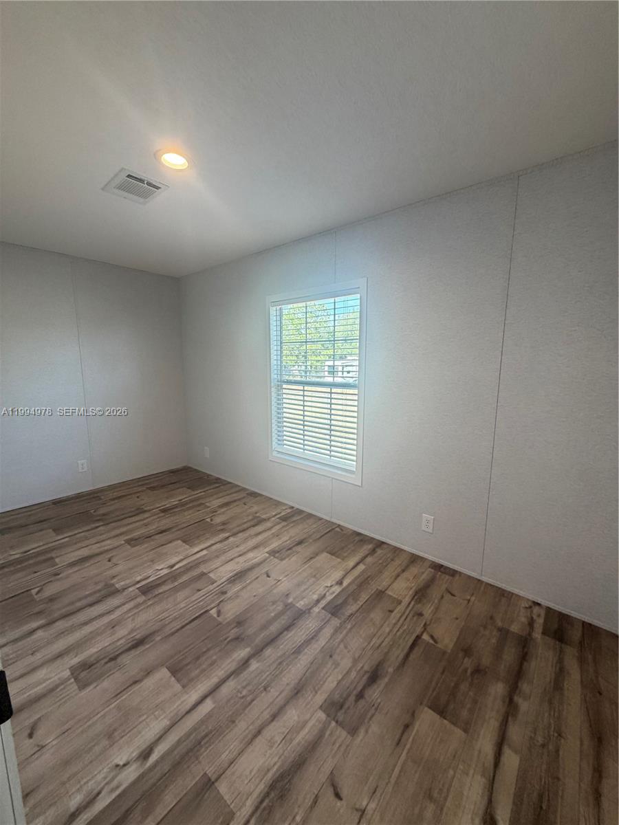 130 North Granja Street Clewiston, FL 33440 - Photo 3 of 10 an empty room with wooden floor and windows