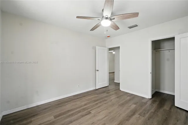 an empty room with wooden floor and ceiling fan