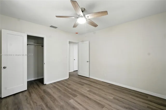 an empty room with wooden floor and ceiling fan