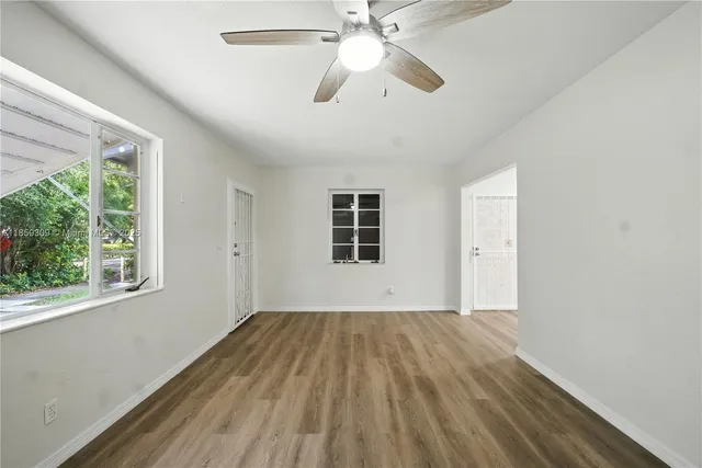 a view of empty room with wooden floor and fan