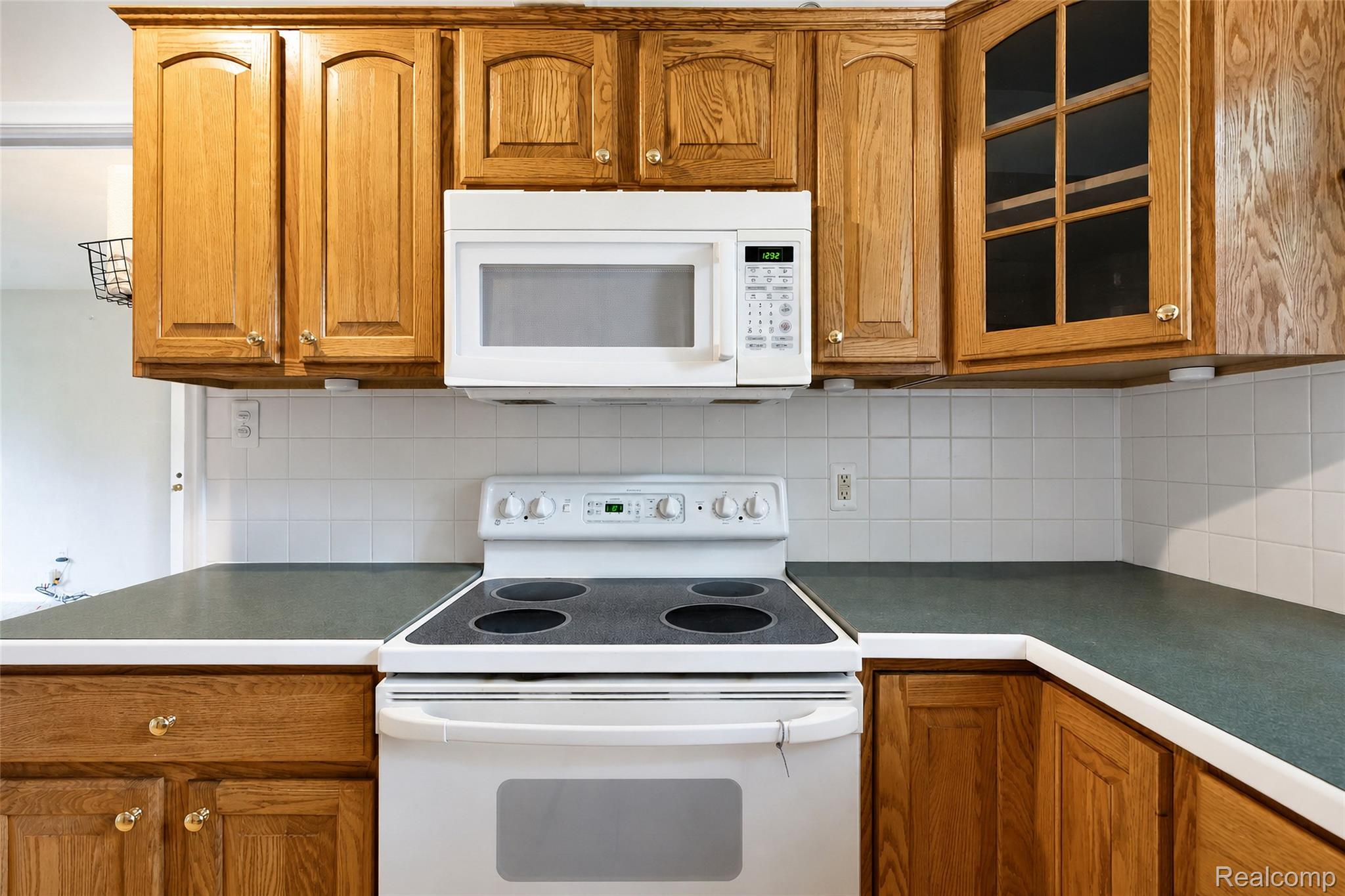 1846 Pembroke Road Birmingham, MI 48009 - Photo 25 of 37 Kitchen featuring wood cabinetry, white tile backsplash, a built-in microwave, and a white electric range
