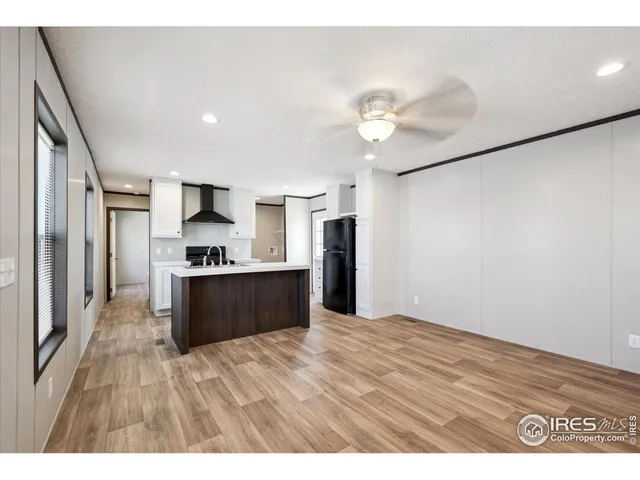 a large kitchen with kitchen island a stove a refrigerator a sink dishwasher with wooden floor and cabinets