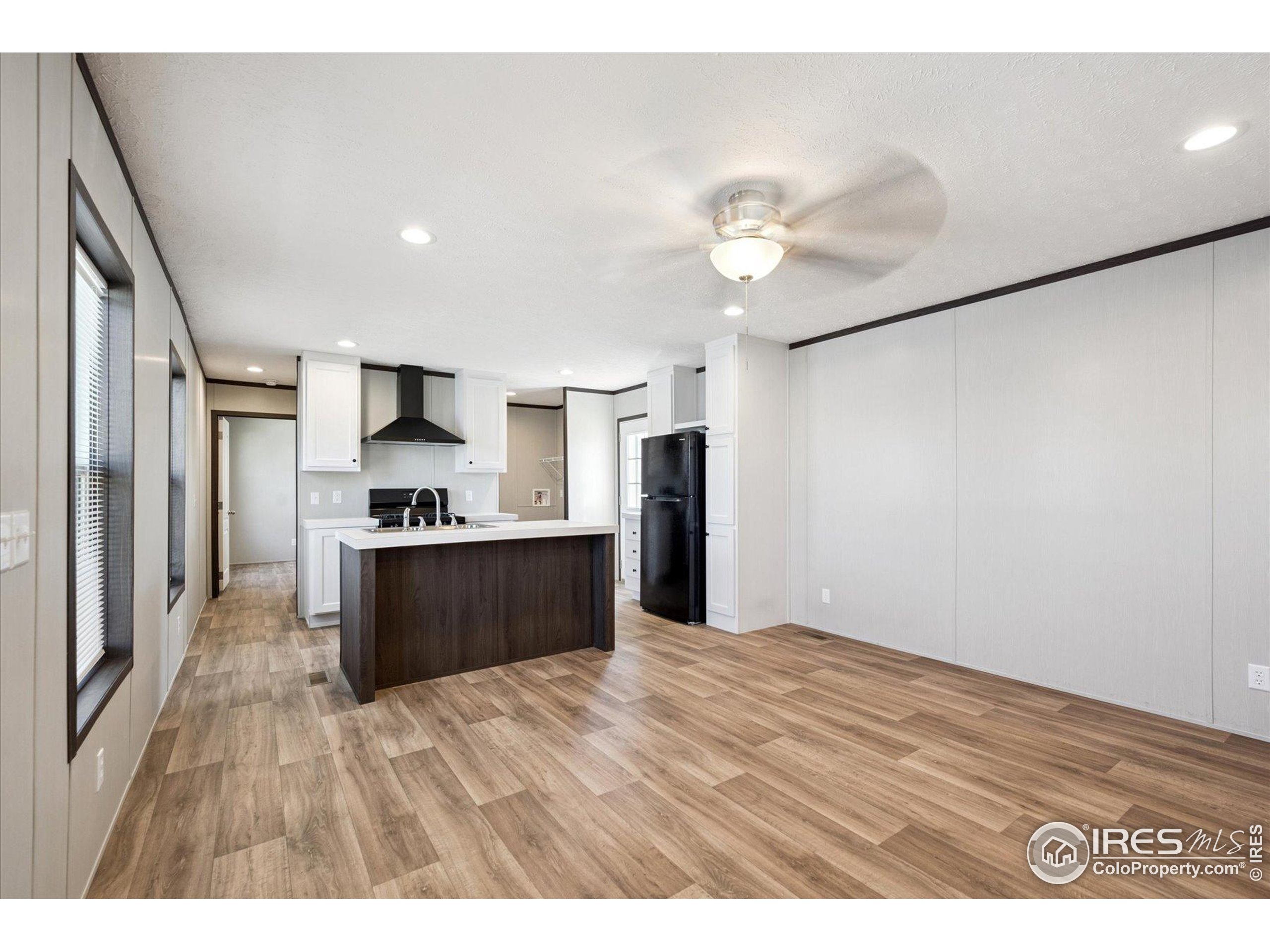 830 1st Street, Unit 2 Pierce, CO 80650 - Photo 8 of 16 a large kitchen with kitchen island a stove a refrigerator a sink dishwasher with wooden floor and cabinets