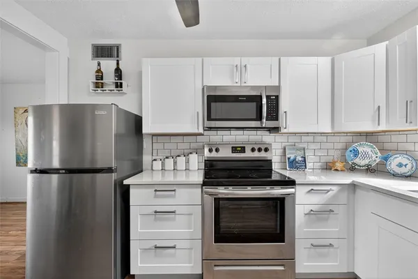 a kitchen with refrigerator a microwave a stove and cabinets
