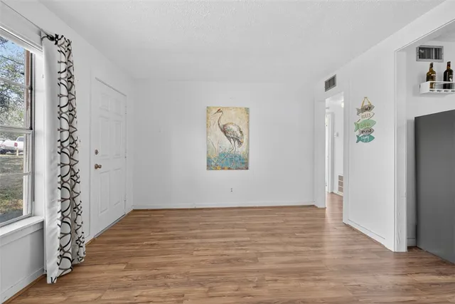 a view of an empty room with window and wooden floor