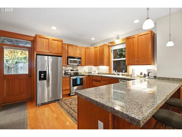 a kitchen with kitchen island granite countertop a sink a counter top stainless steel appliances and cabinets