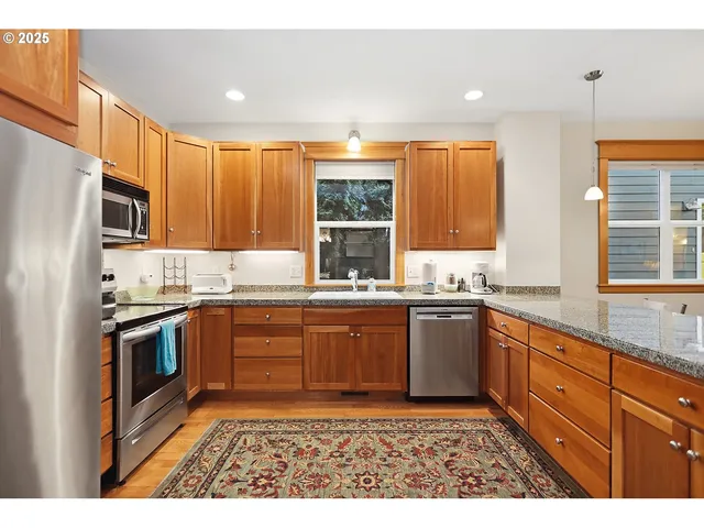 a kitchen with stainless steel appliances granite countertop a stove a sink dishwasher a refrigerator and a microwave