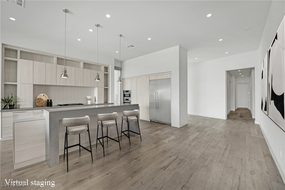 658 Falcon Summit Court Henderson, NV 89012 - Photo 11 of 99 Kitchen featuring modern cabinets, a kitchen bar, a large island with sink, recessed lighting, and backsplash