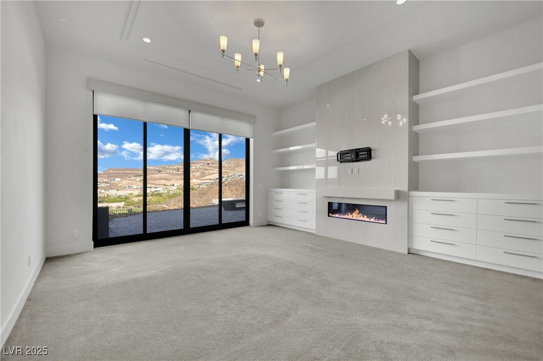 658 Falcon Summit Court Henderson, NV 89012 - Photo 29 of 99 Unfurnished living room featuring light carpet, a large fireplace, a chandelier, and recessed lighting