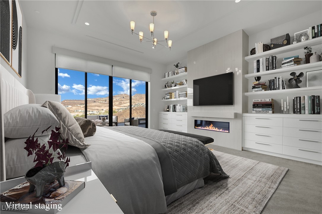 658 Falcon Summit Court Henderson, NV 89012 - Photo 30 of 99 Bedroom with carpet floors, access to exterior, a glass covered fireplace, a chandelier, and recessed lighting