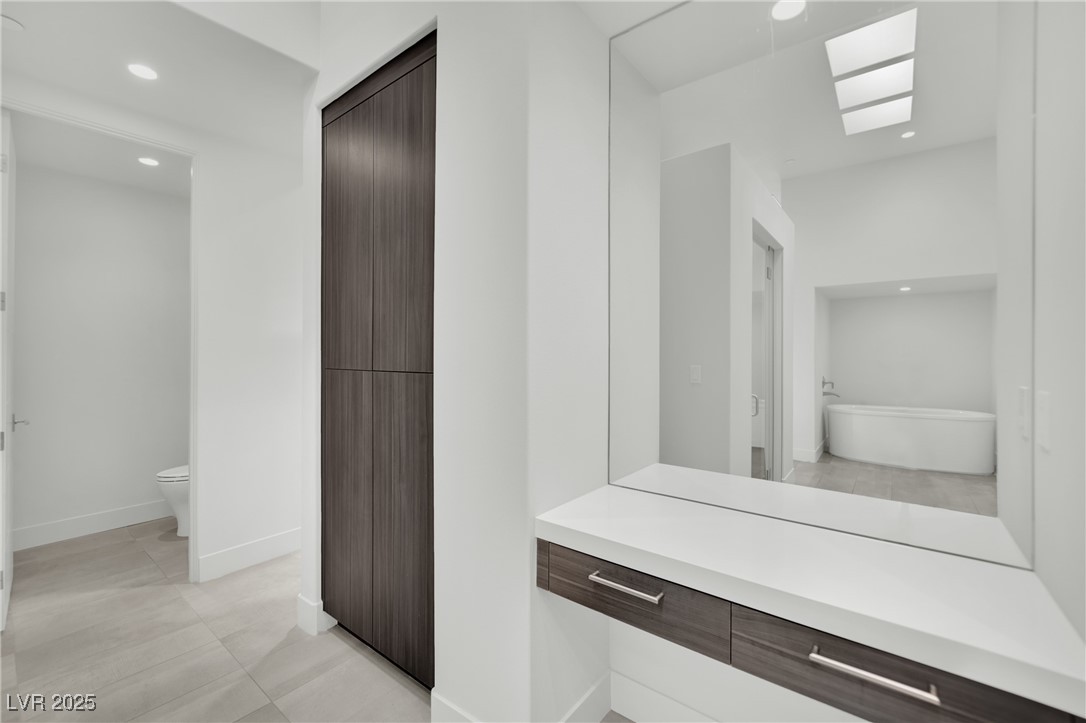 658 Falcon Summit Court Henderson, NV 89012 - Photo 36 of 99 Bathroom with recessed lighting, a freestanding bath, light tile patterned floors, and a skylight