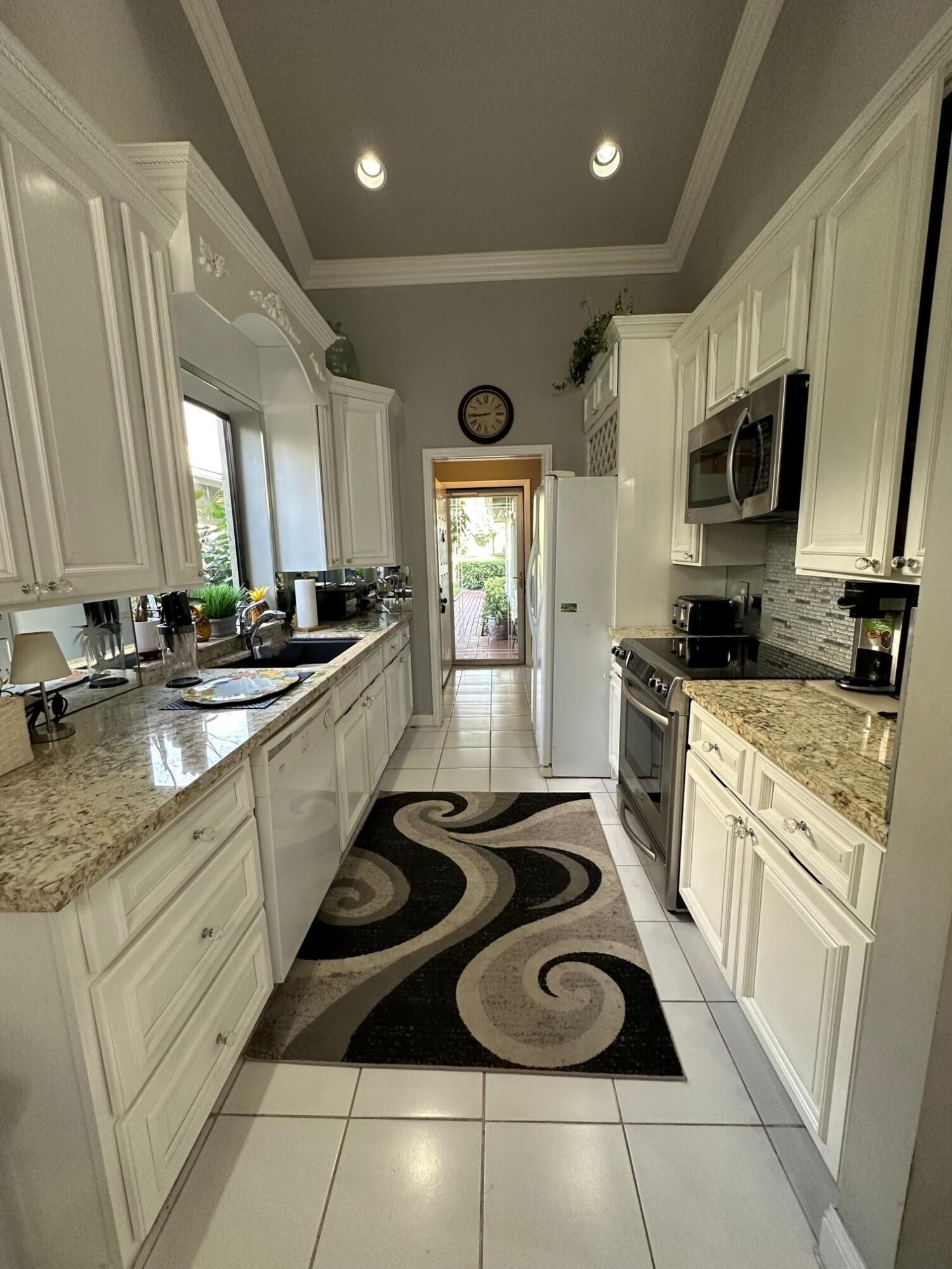 150 Cape Pointe Circle Jupiter, FL 33477 - Photo 7 of 22 a kitchen with stainless steel appliances kitchen island granite countertop a sink stove a sink dishwasher and white cabinets with wooden floor