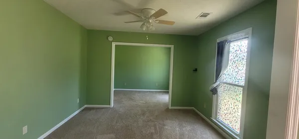 a view of an empty room with windows and chandelier fan