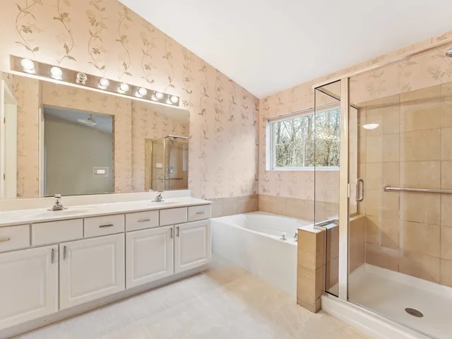 a spacious bathroom with a tub sink shower and mirror