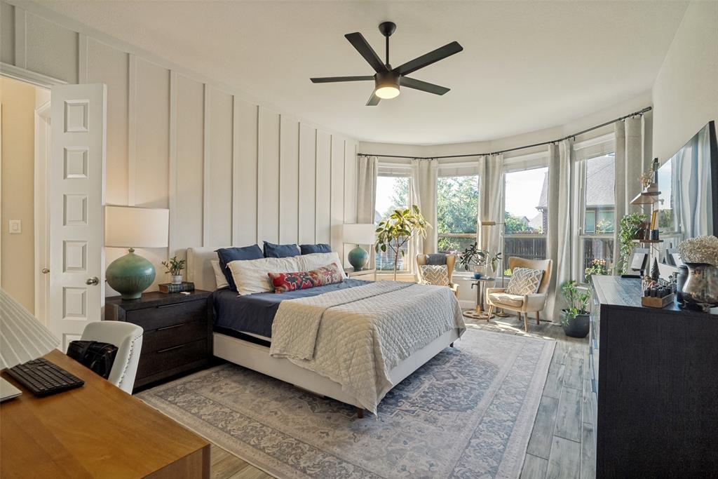 14948 Gentry Drive Aledo, TX 76008 - Photo 19 of 25 Spacious bedroom featuring a bay window, wood-finish flooring, a contemporary ceiling fan, and board and batten accent wall
