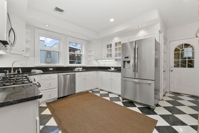 a kitchen with a sink a refrigerator and white cabinets