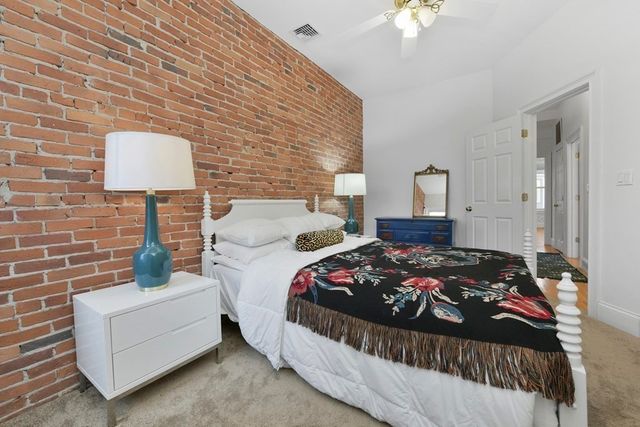 a bedroom with a bed a lamp and a fireplace