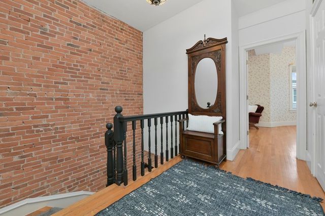 a view of a hallway with wooden floor and a bathroom