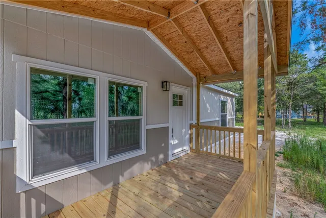 a porch with a table and chairs next to a yard