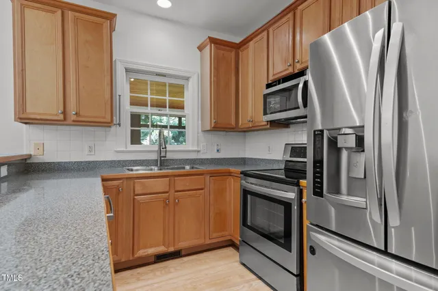 a kitchen with stainless steel appliances granite countertop a refrigerator and a sink