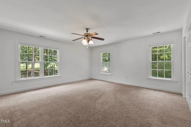 an empty room with windows and chandelier fan