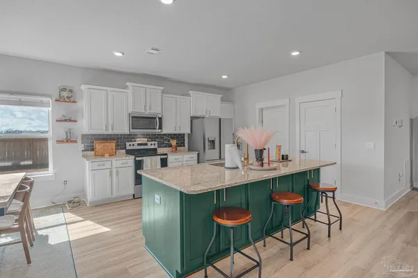 a kitchen with stainless steel appliances granite countertop a table chairs sink and cabinets
