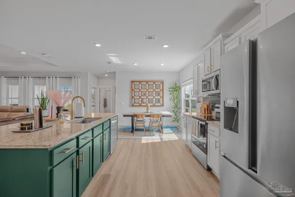 a kitchen with stainless steel appliances granite countertop a refrigerator oven a sink dishwasher and white cabinets with wooden floor