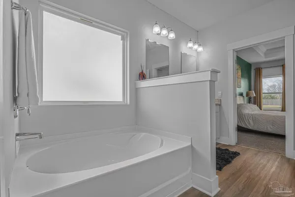 a bathroom with a bathtub a mirror a lamp and window