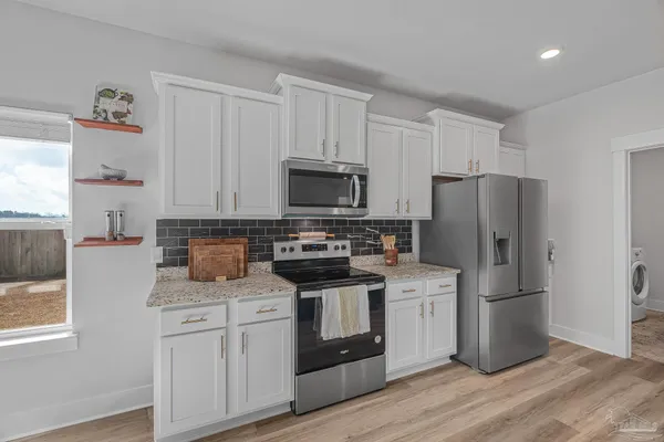 a kitchen with a refrigerator stove and white cabinets
