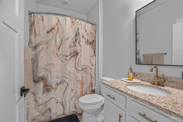 a bathroom with a granite countertop sink toilet and a mirror