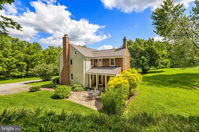 a view of a house with a big yard plants and large trees