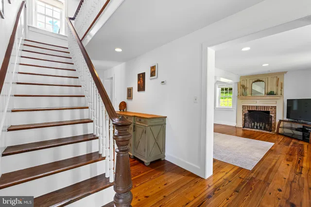 a view of a livingroom with wooden floor fireplace and staircase