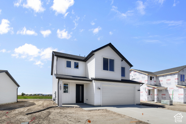 537 South 1150 West Logan, UT 84321 - Photo 3 of 33 Two-story residence featuring white horizontal siding, vertical siding accents, a black roof, and an attached two-car garage