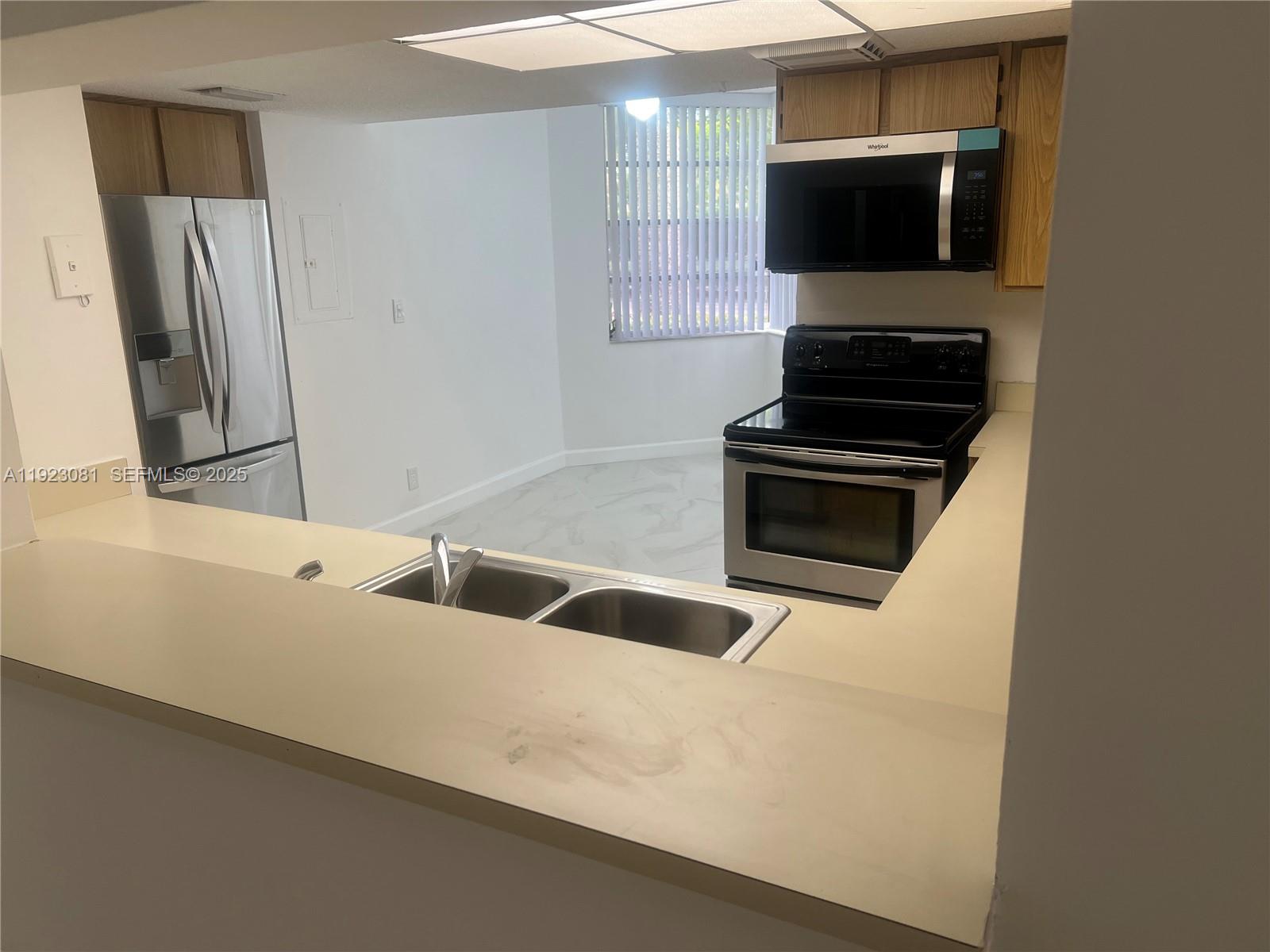 9510 Seagrape Drive, Unit 101 Davie, FL 33324 - Photo 8 of 18 a kitchen with stainless steel appliances a stove a microwave and a sink