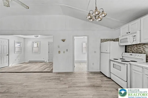 a kitchen with stainless steel appliances granite countertop a refrigerator a stove oven and white cabinets with wooden floor