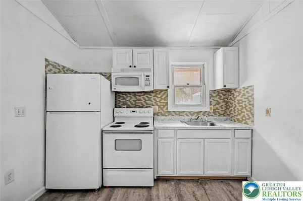 a kitchen with white cabinets and white appliances