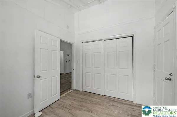 an empty room with wooden floor cabinet and windows