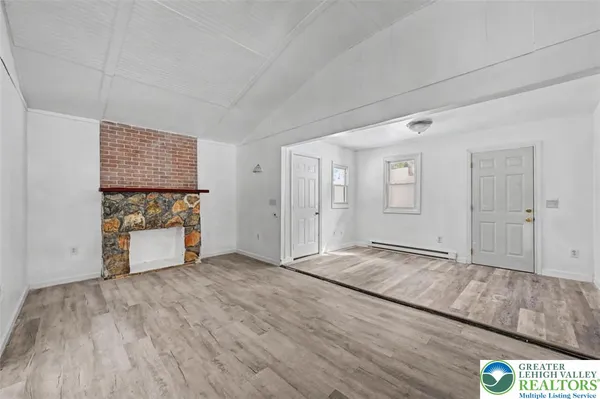 a view of an empty room with kitchen and window