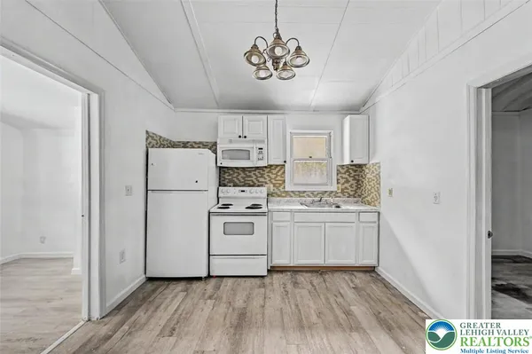 a kitchen with white cabinets and white appliances