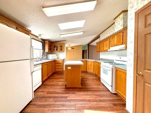 a kitchen with stainless steel appliances granite countertop a refrigerator a sink dishwasher and a stove with wooden floor