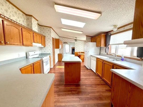 a large kitchen with stainless steel appliances kitchen island granite countertop wooden floors and a view of living room
