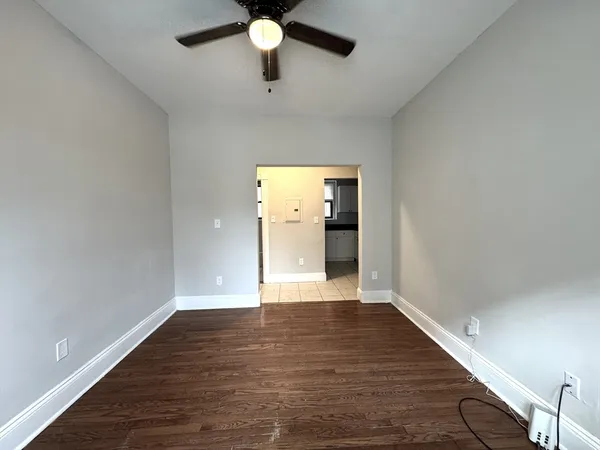 a view of an empty room with wooden floor and a window
