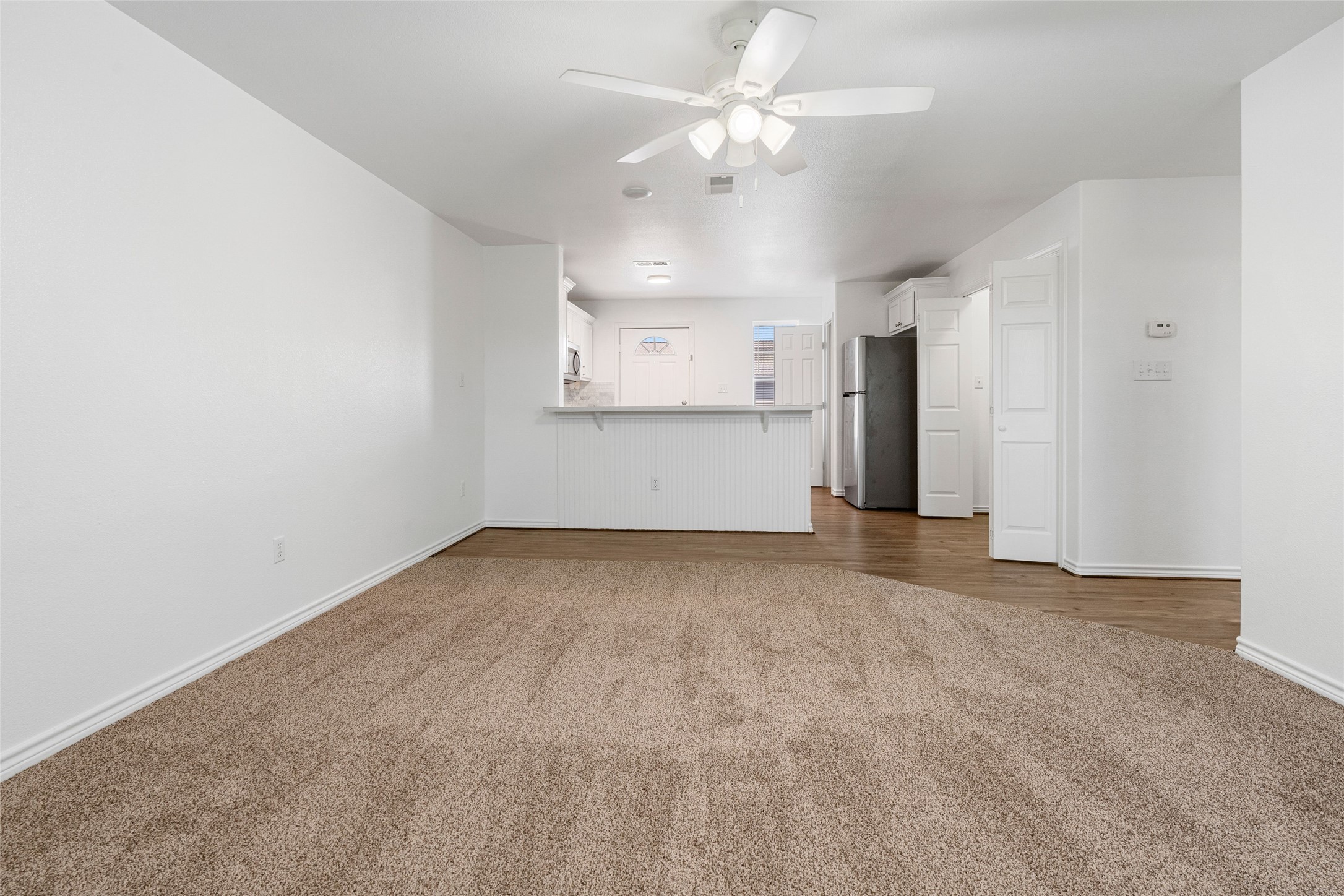 210 Brazos Street, Unit 202 Brazoria, TX 77422 - Photo 12 of 20 an empty room with a kitchen and a ceiling fan