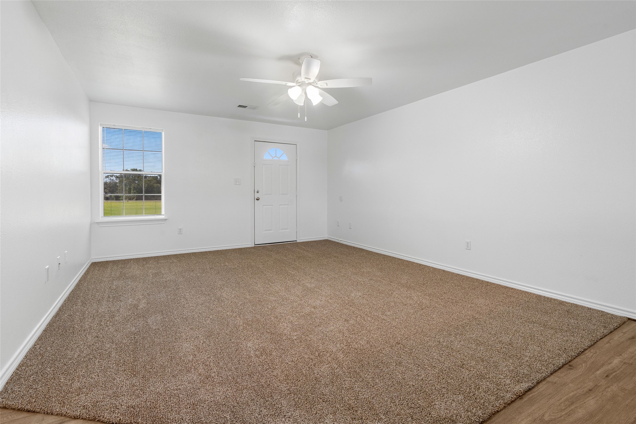 210 Brazos Street, Unit 202 Brazoria, TX 77422 - Photo 8 of 20 an empty room with a chandelier fan and windows